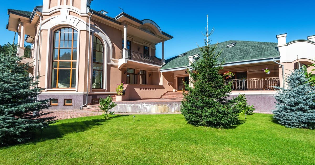 Modern two-storey house with a large green lawn under a bright blue sky