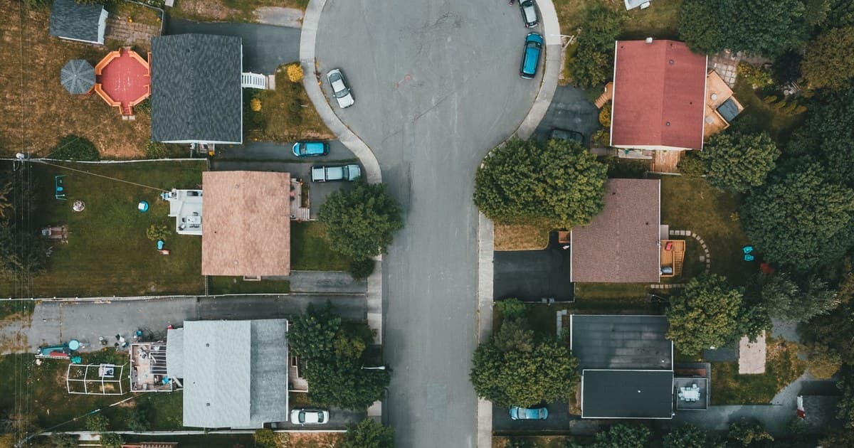 Aerial view of a suburban residential neighborhood with houses, streets and trees