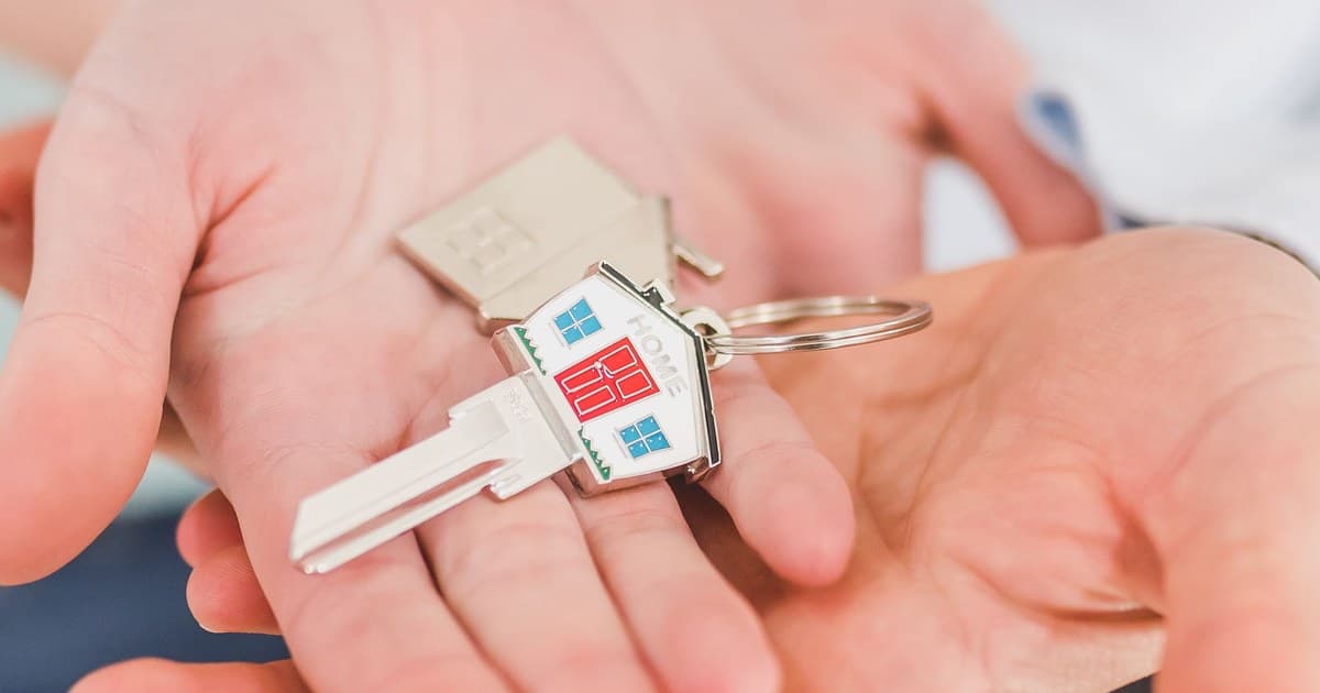 Hands holding a house-shaped keychain, symbolizing new home ownership through a home loan