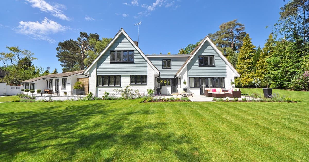 Suburban house with a large green lawn under a clear blue sky