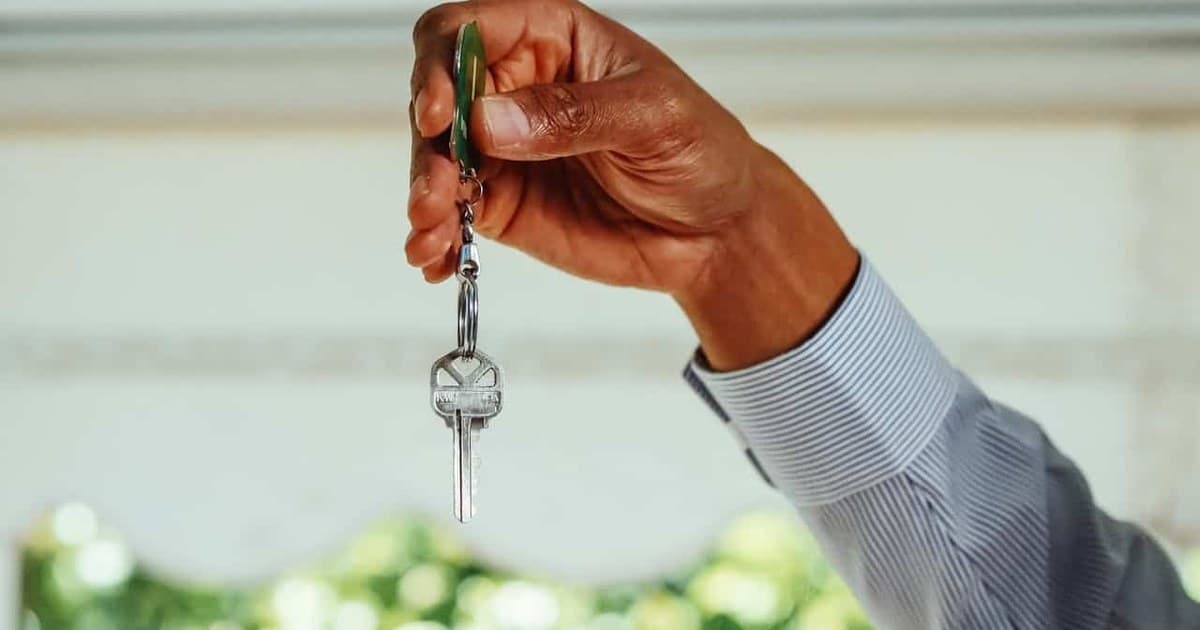 A hand holding a house key, symbolising the choice between renting and buying a home in Lahore